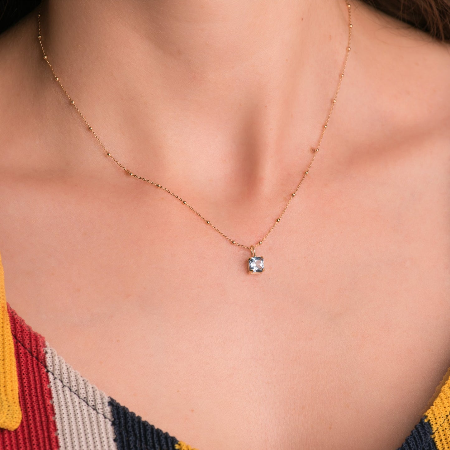 18K COLGANTE ORO AMARILLO CUADRADO CON GARRAS Y PIEDRA COLOR AGUAMARINA 5,5 X 5,5 MM.